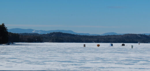 Image of various structures on Long Lake where people are ice fishing. A sturdy foundation of lake ice is necessary for this activity